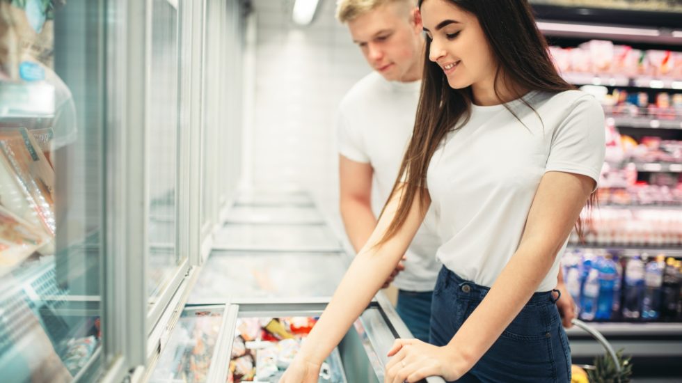 Young couple choosing frozen goods in supermarket
